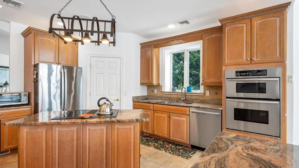 A kitchen with wooden cabinets, stainless steel appliances, and a central island.