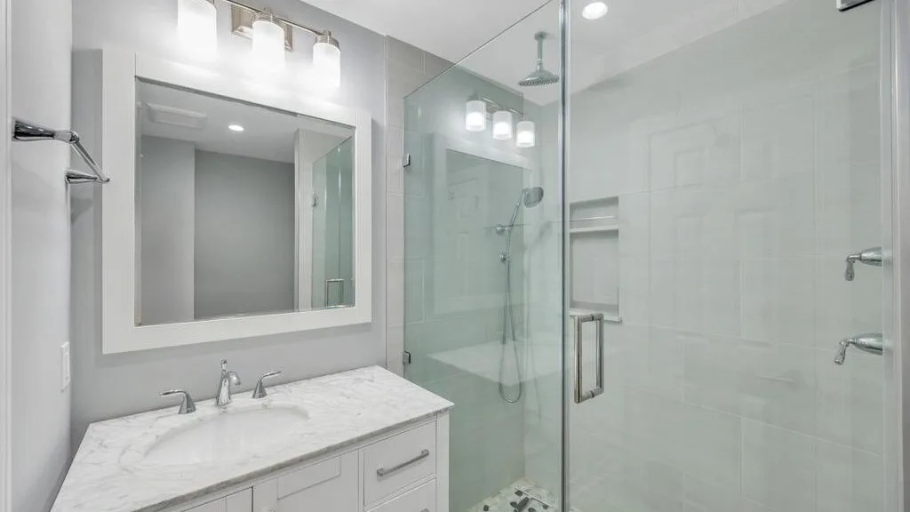 A bright bathroom with a vanity and a glass shower.