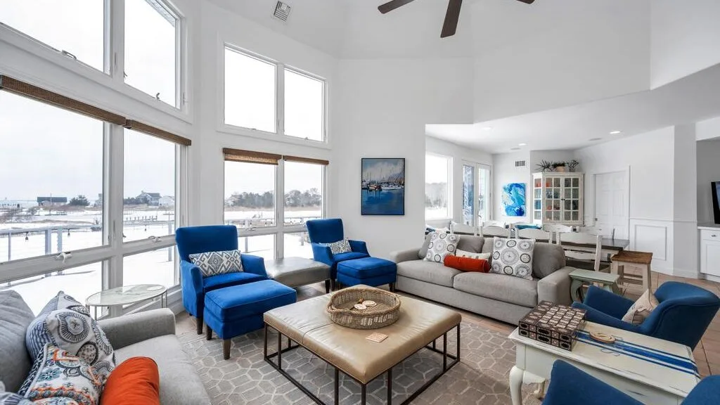 A bright living room with seating around a coffee table and large windows.