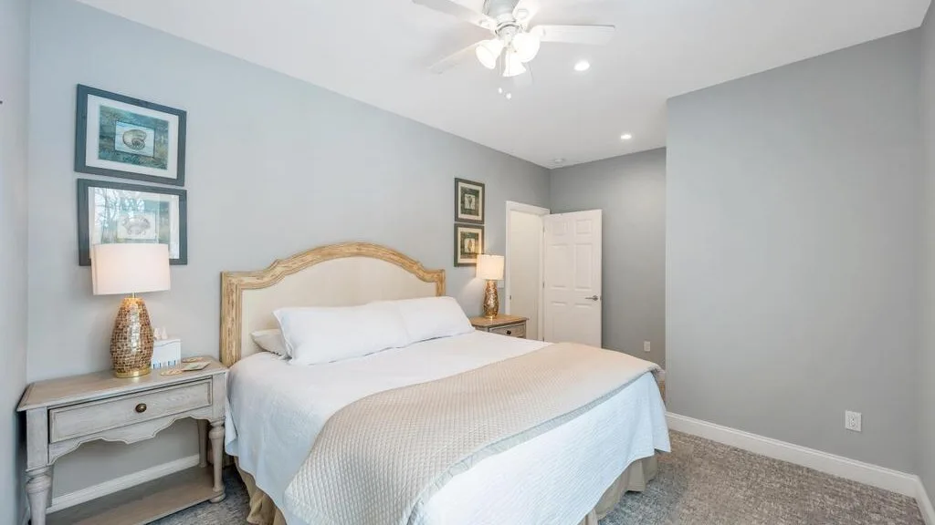 A bedroom with a neatly made bed and framed pictures on the wall.