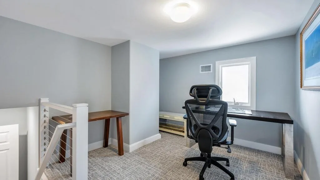 A bright home office with a desk, computer chair, and window.