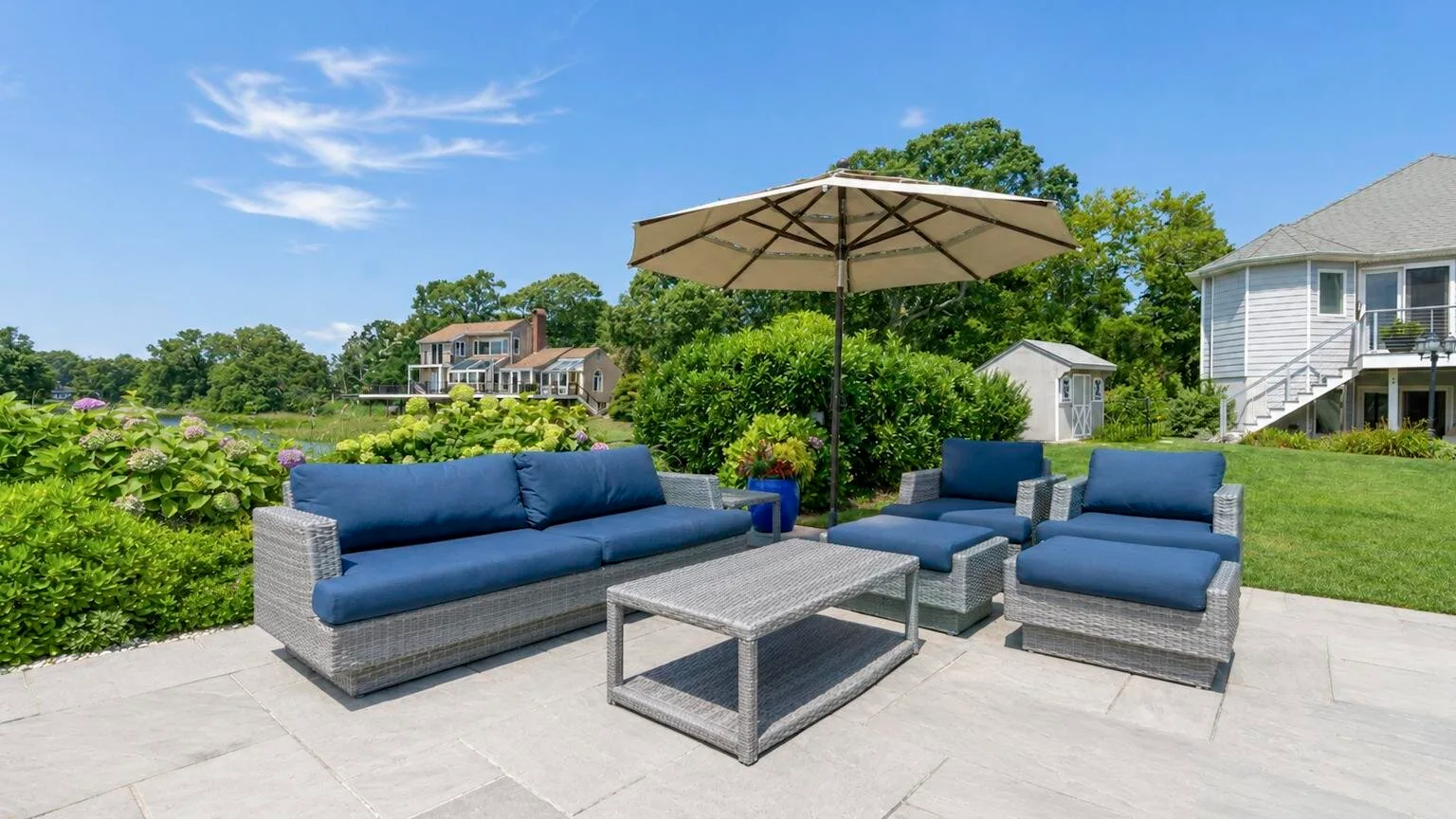 An outdoor patio seating area with blue cushions beneath a large umbrella.