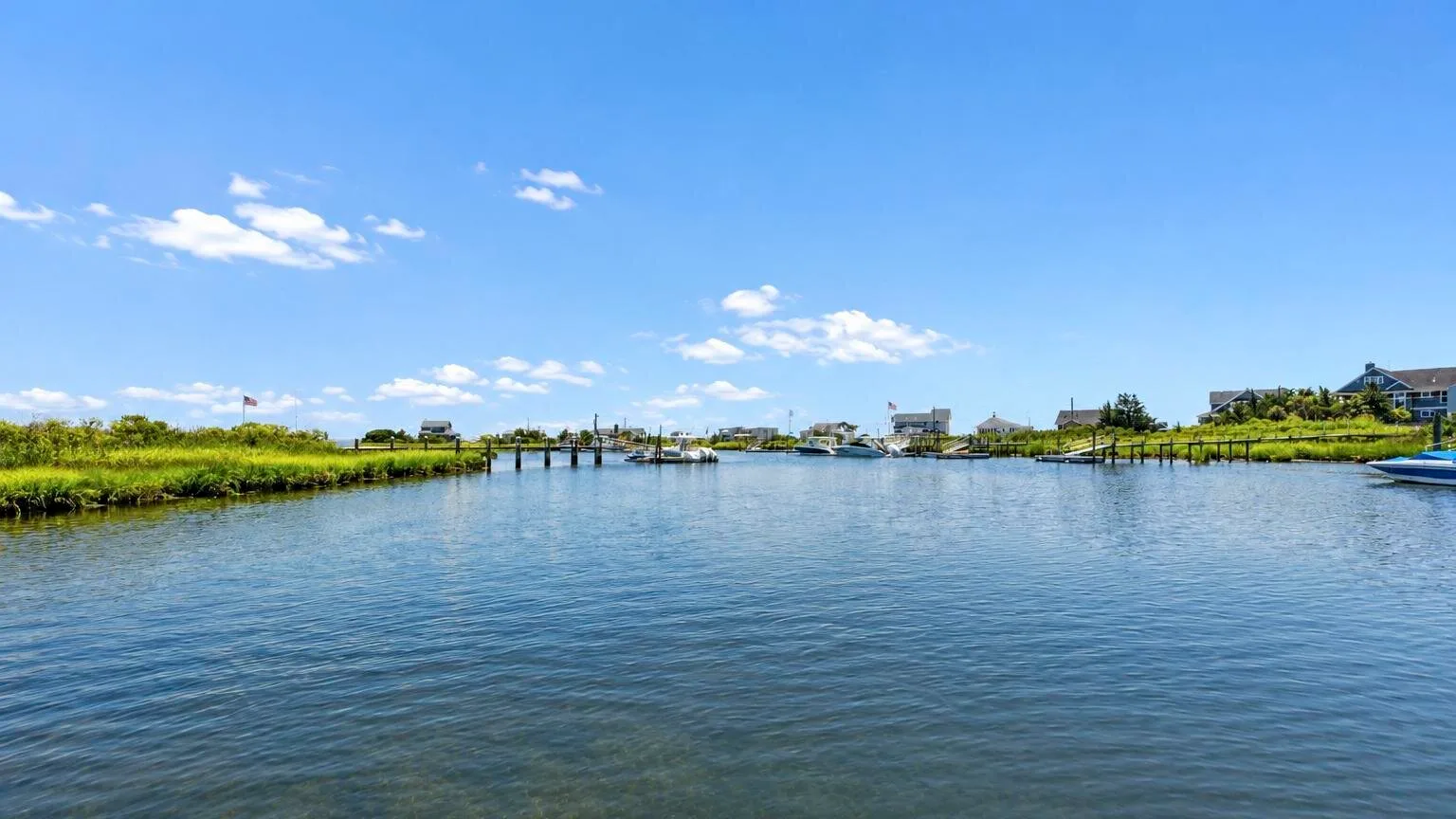 A broad waterway runs between grassy banks beneath a clear blue sky.
