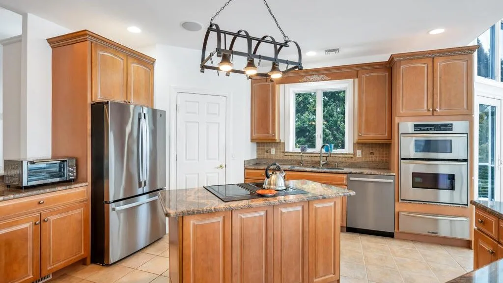A kitchen with wooden cabinets, stainless steel appliances, and a central island.