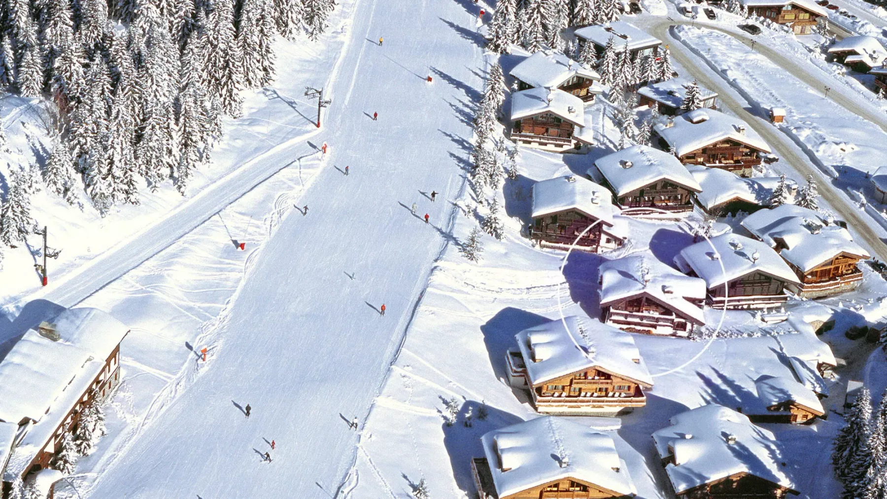 Vista aérea de una pista de esquí nevada junto a un grupo de edificios.