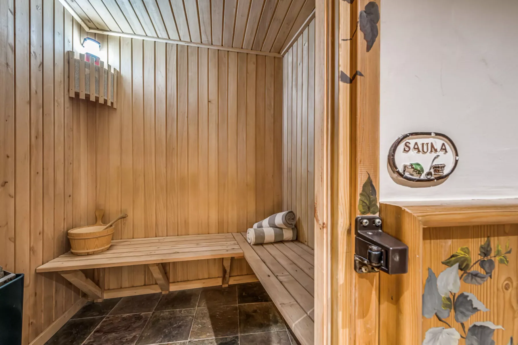 Una sauna revestida de madera, con bancos escalonados y una ventana pequeña.