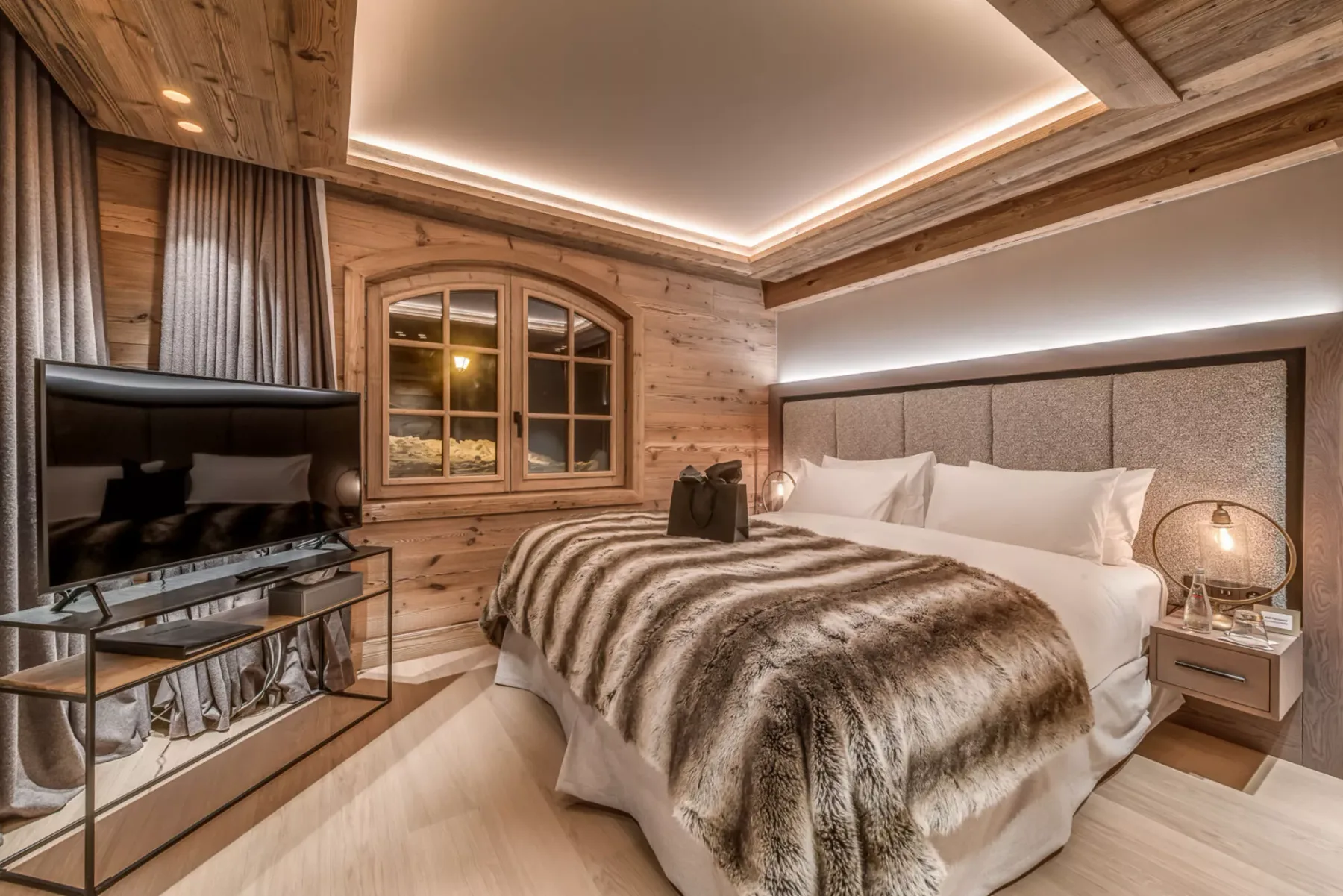 Un dormitorio revestido de madera con una cama grande y un televisor.