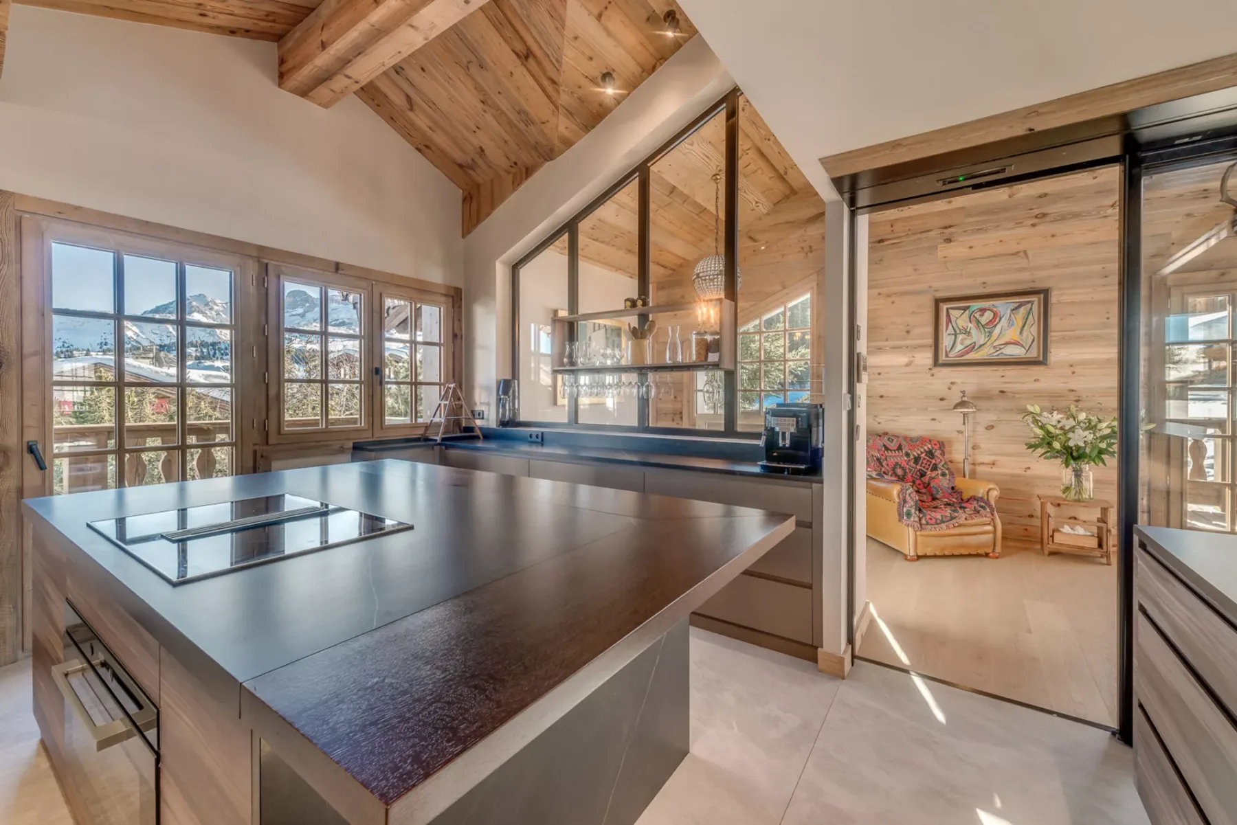 A bright kitchen with a large island and windows overlooking a snowy landscape.