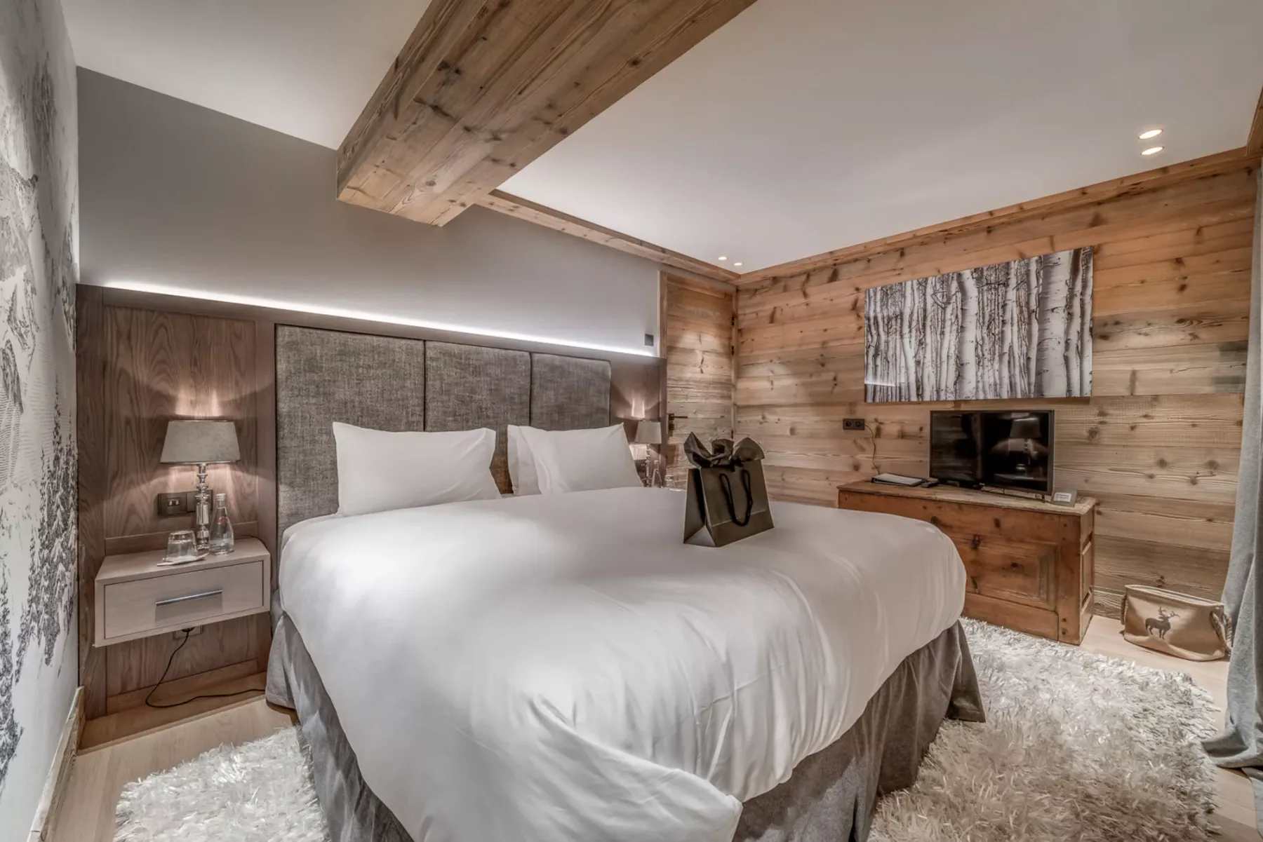 Un dormitorio con una cama grande, paredes revestidas de madera y un televisor.