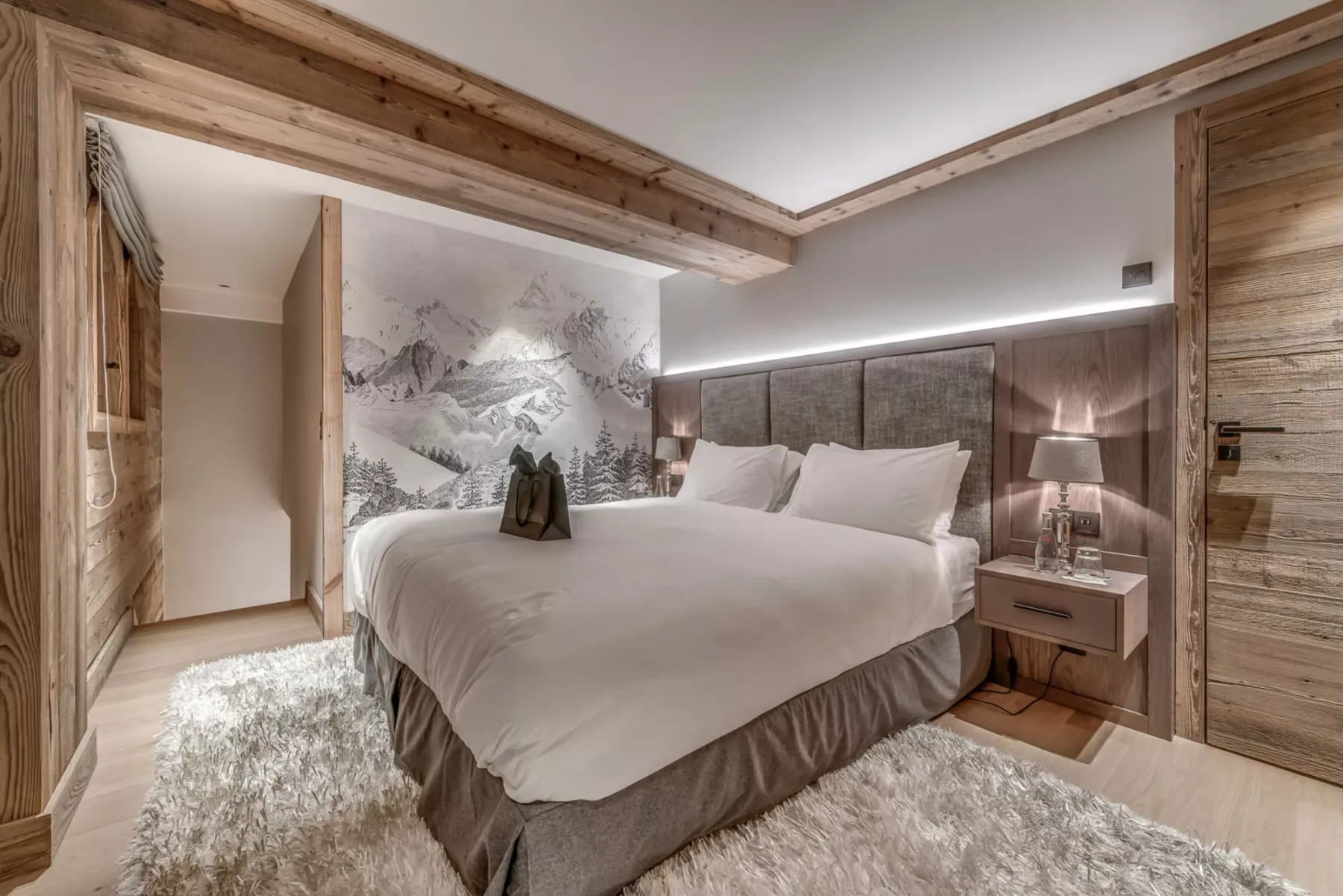 Un dormitorio con una cama grande, un mural de montañas y molduras de madera.