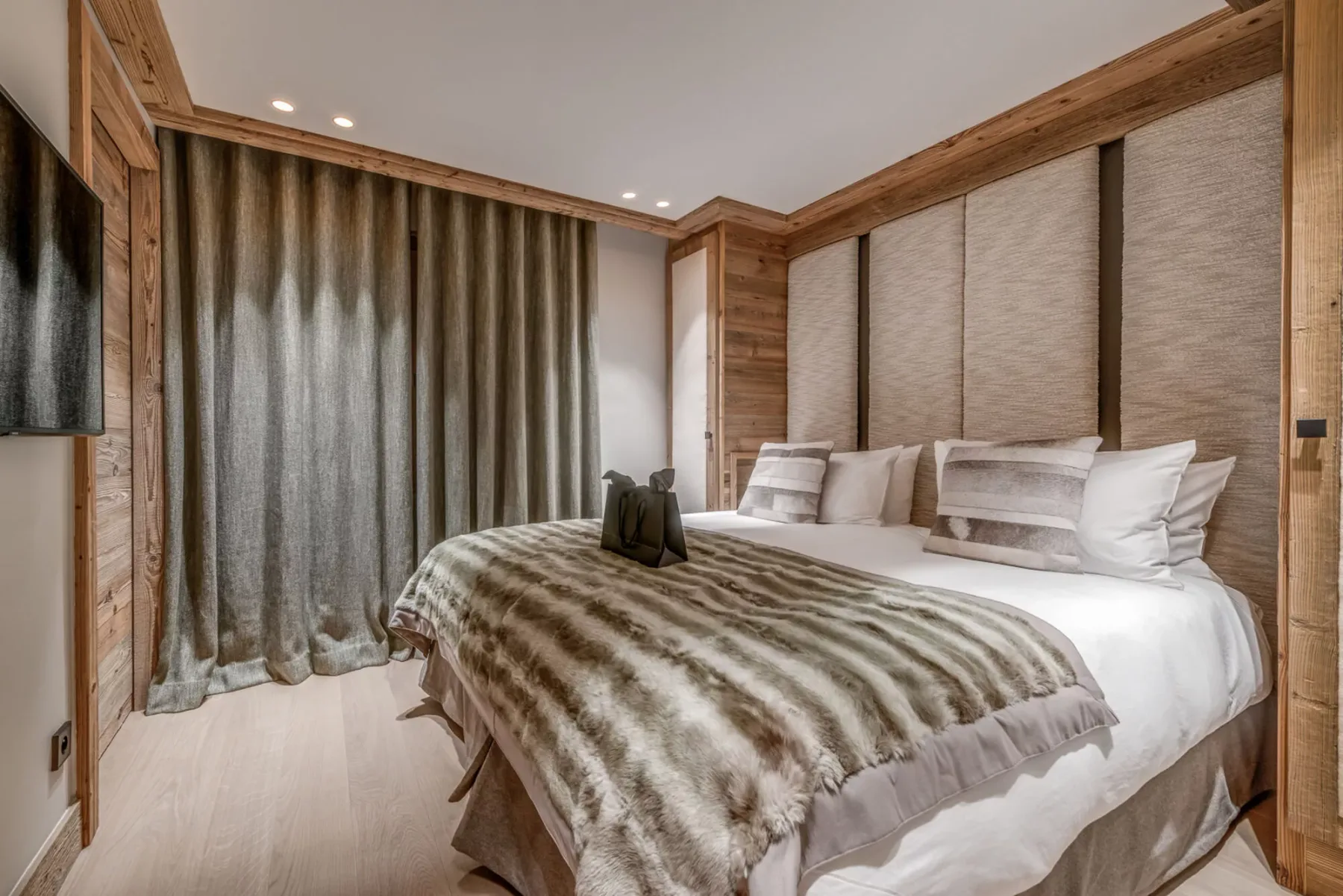 Un dormitorio con una cama cubierta por una manta a rayas junto a cortinas largas.