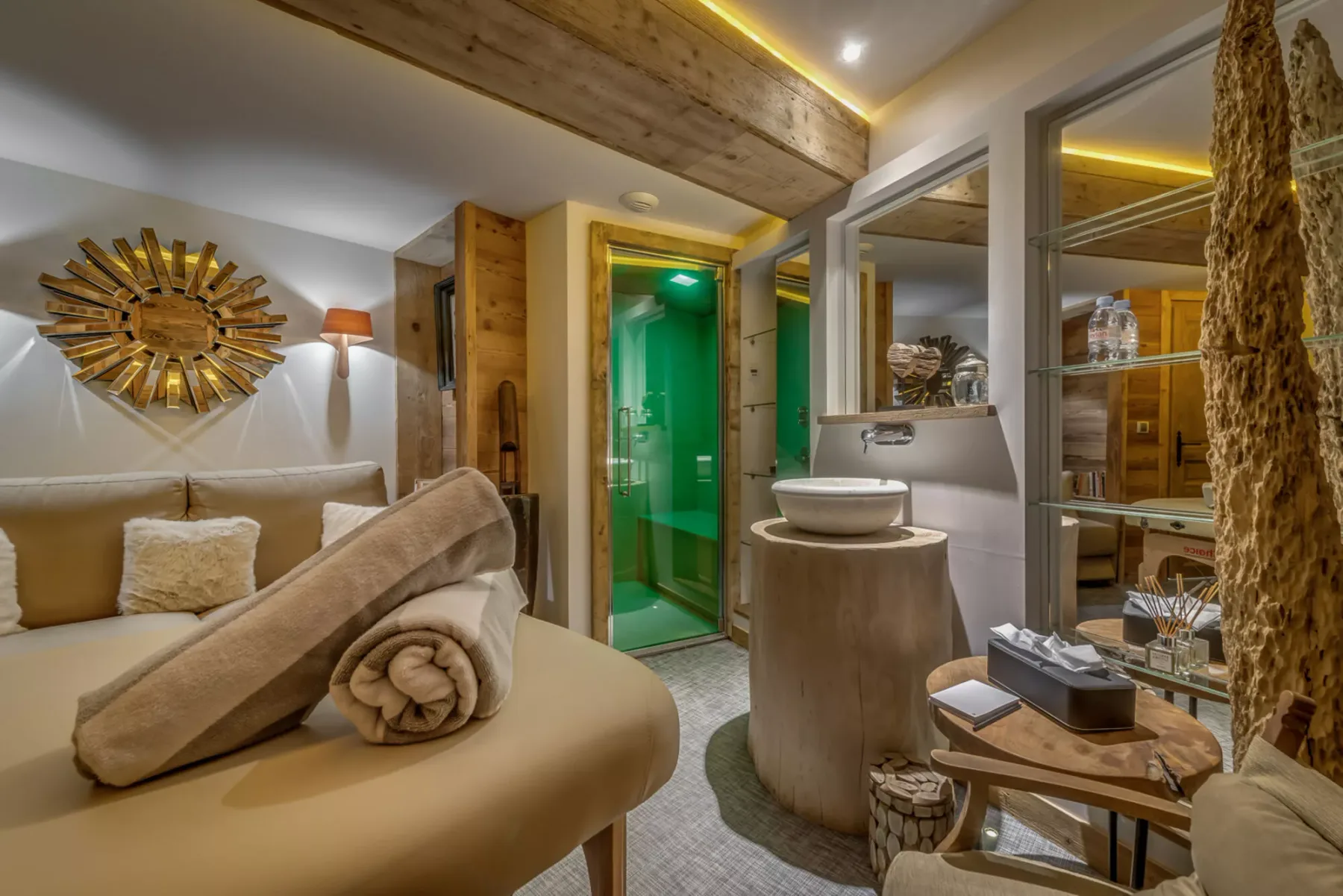 Zona de estar del dormitorio junto a una ducha de vidrio y un lavabo redondo.