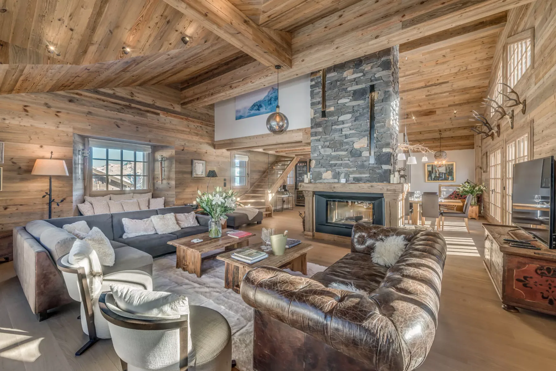 A spacious living room with seating arranged around a stone fireplace.