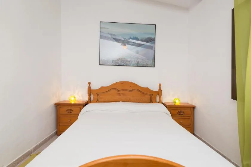 Un dormitorio con una cama bien tendida, cabecero de madera y mesillas a juego.
