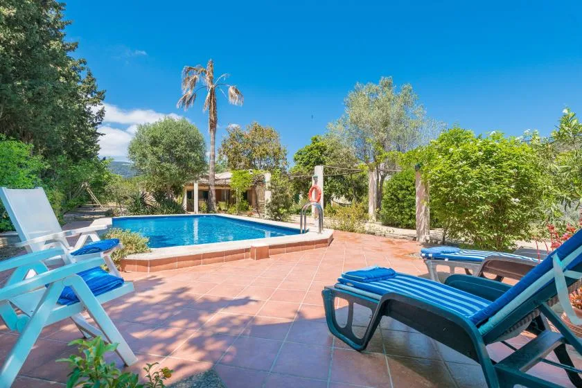 Una piscina al aire libre está rodeada por un patio de baldosas y asientos reclinables.