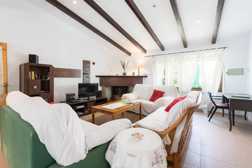 Una sala de estar luminosa con asientos alrededor de una mesa de centro y un televisor.