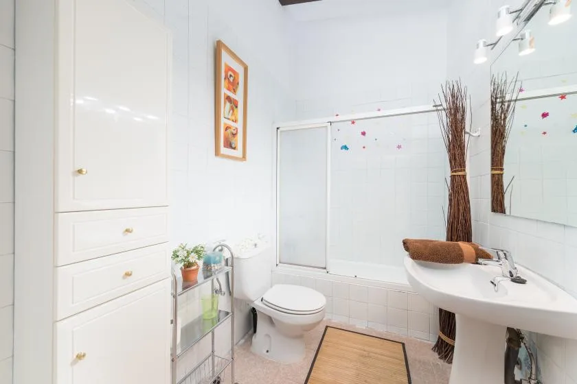 Un baño luminoso con inodoro, lavabo y ducha de vidrio.