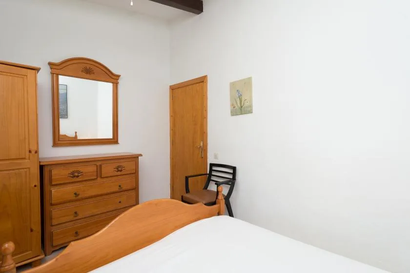 Dormitorio con cama de madera, cómoda y espejo.