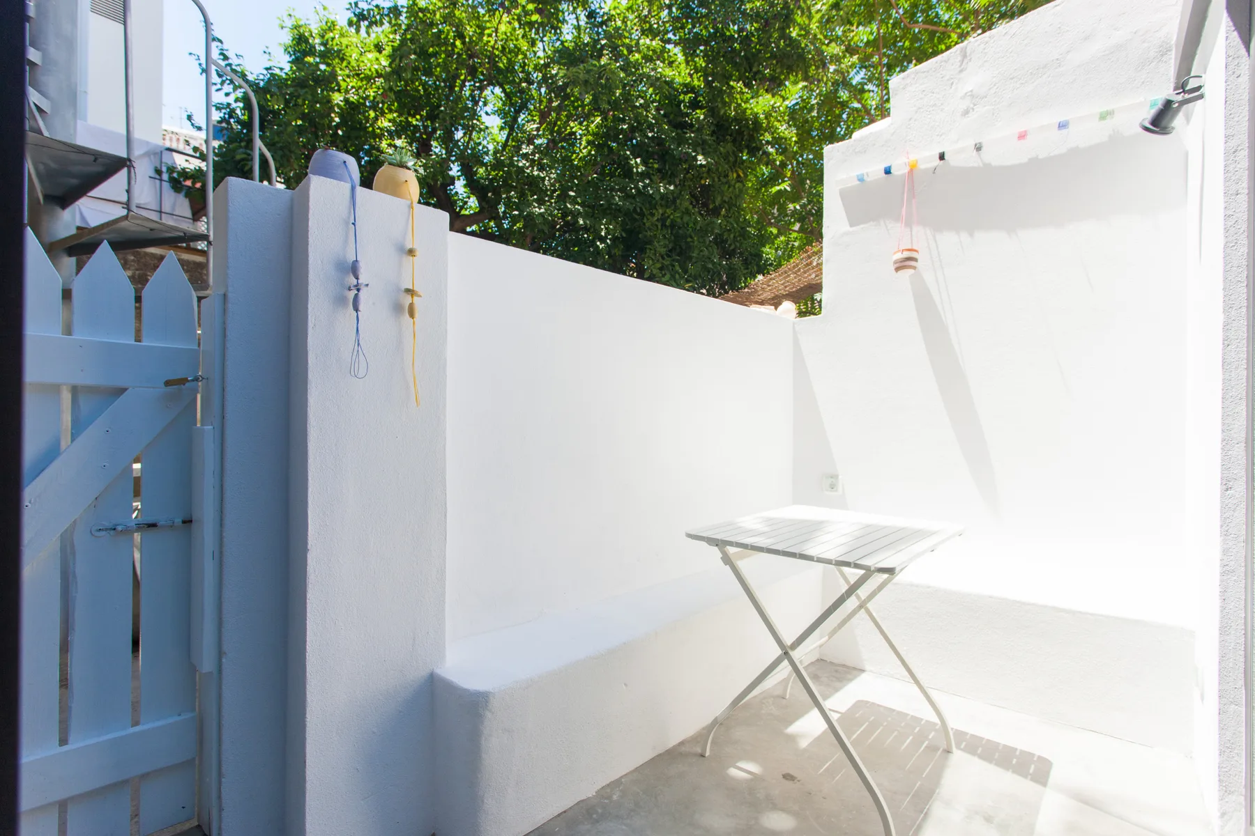 A sunlit outdoor patio with a folding table and white walls.