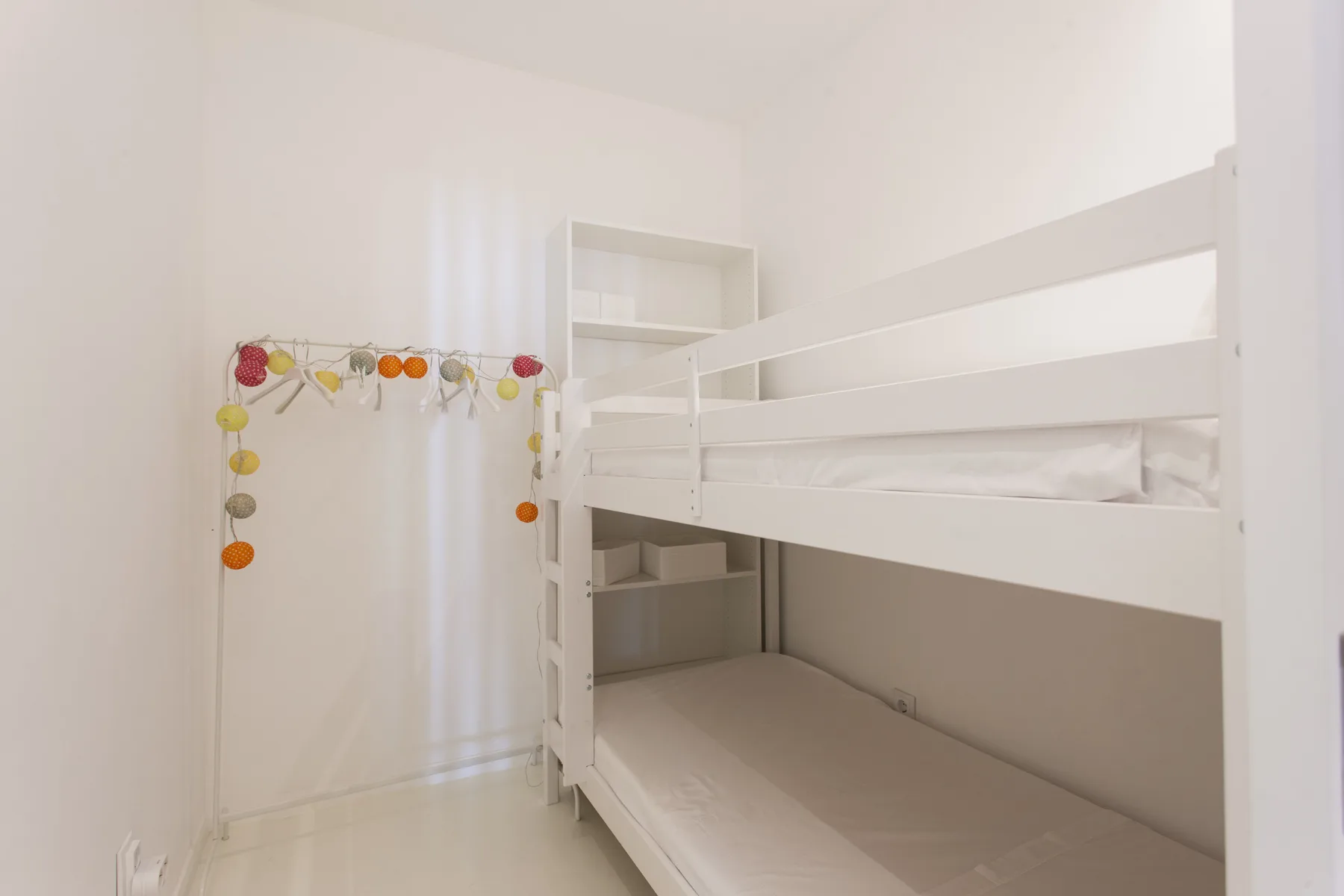 A bunk bed and open shelving are visible in a bright bedroom.