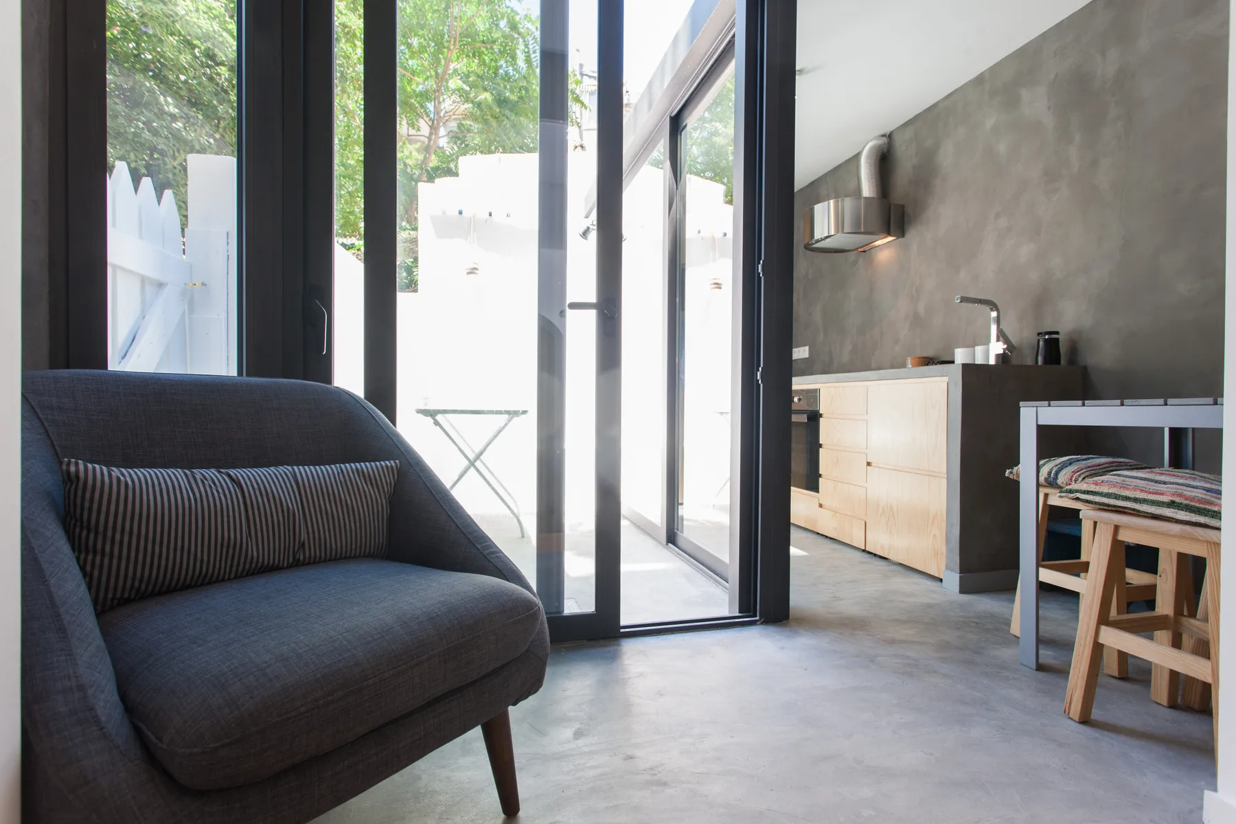 A modern kitchen and seating area opens onto a bright patio.