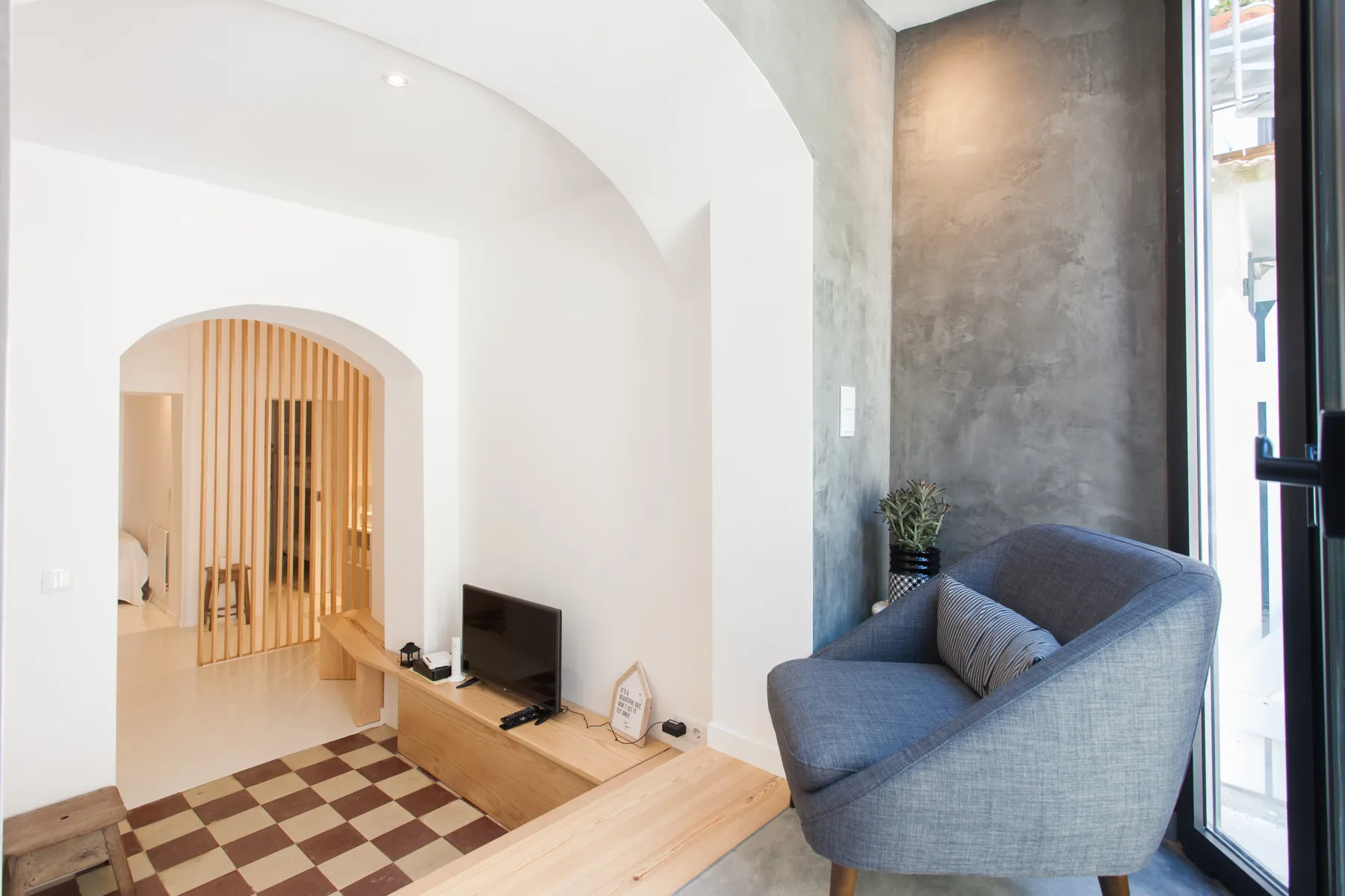 A living area with a blue upholstered seat beside a television.