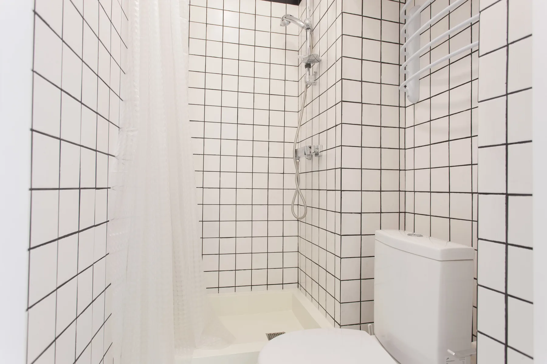 A tiled bathroom with a shower and toilet.