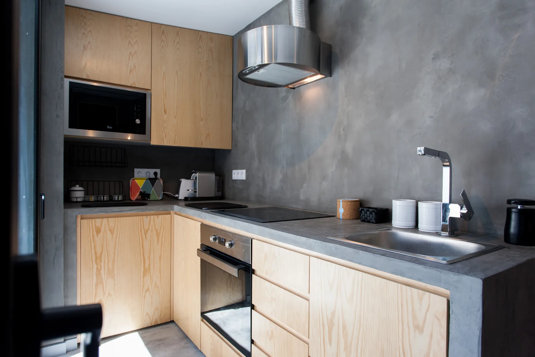 A modern kitchen with light wood cabinetry, a countertop, and a built-in oven.