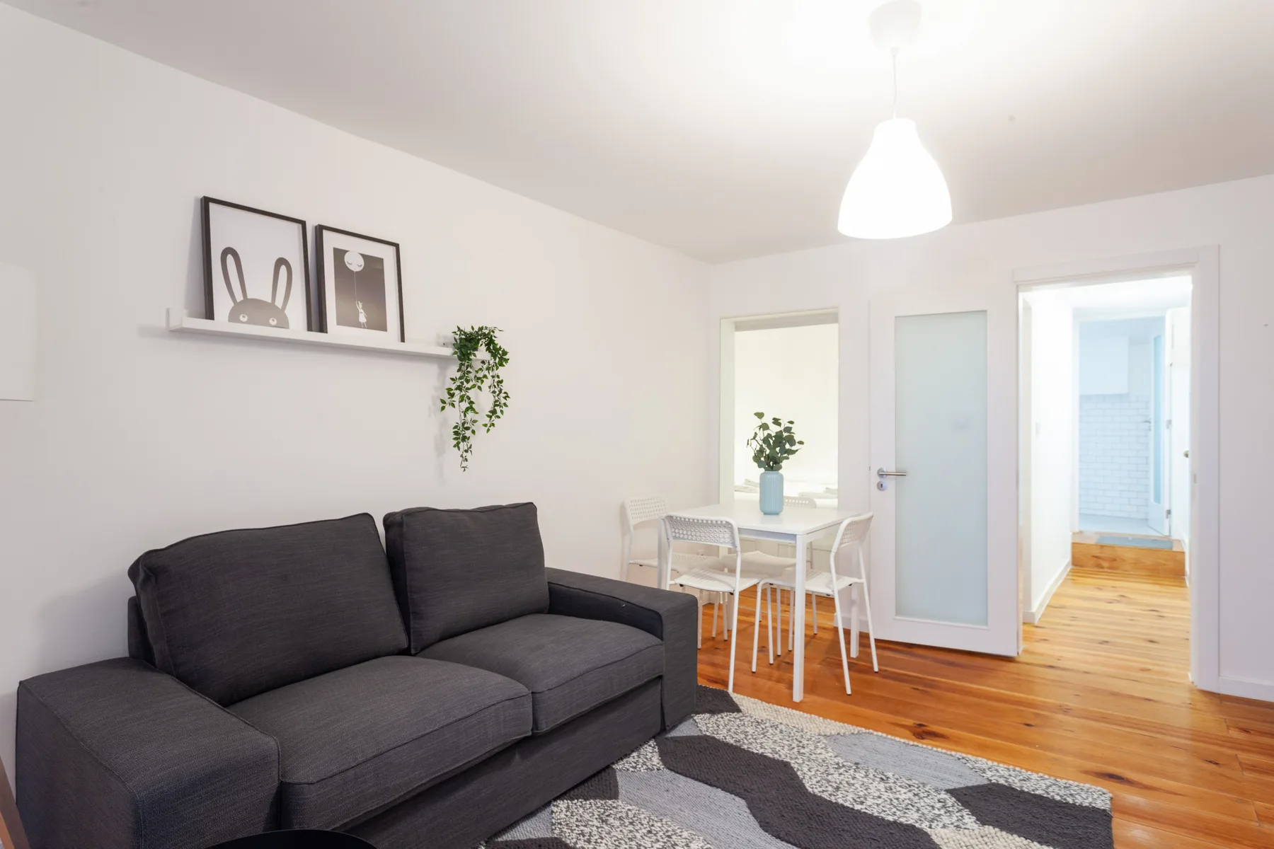 Una sala de estar con asientos oscuros, una pequeña mesa de comedor y una puerta.