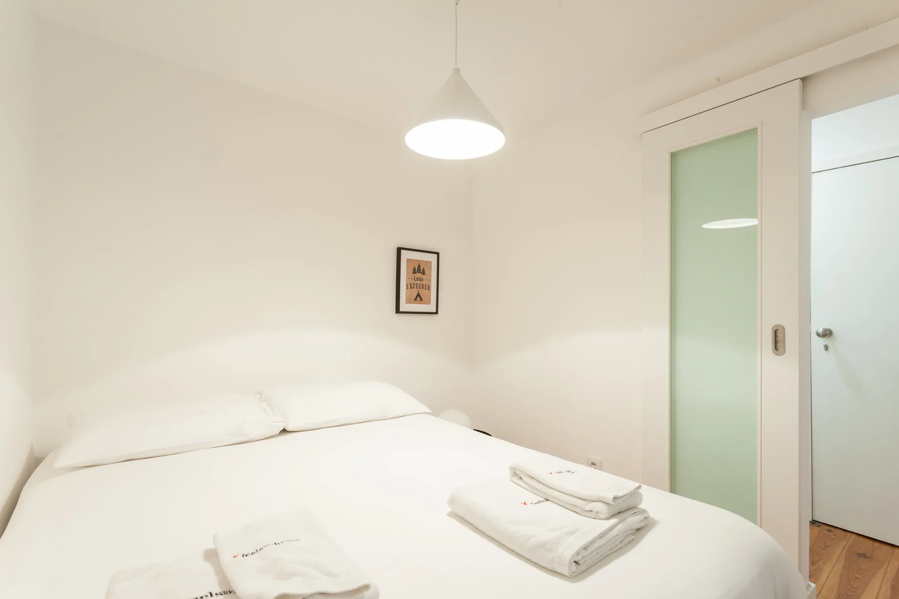 Un dormitorio luminoso con una cama y toallas dobladas.