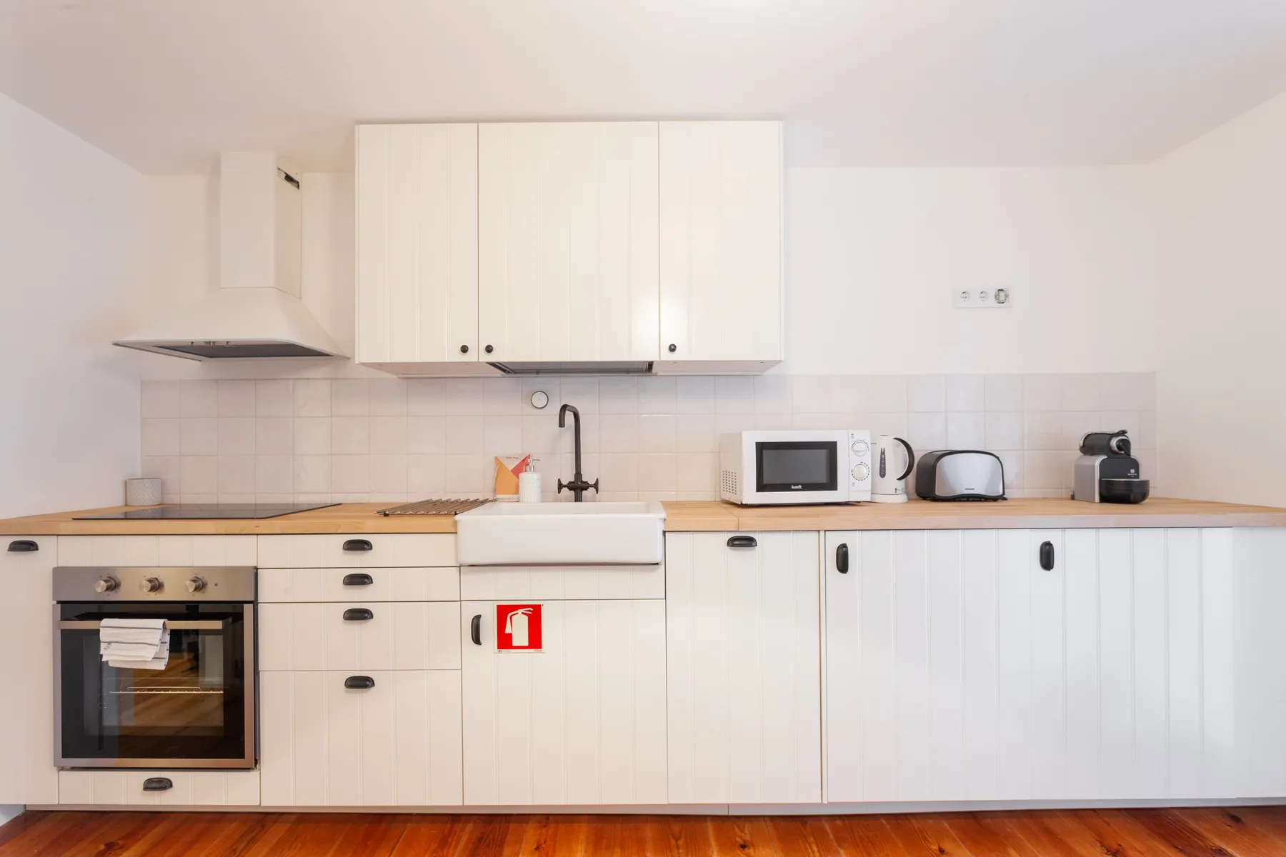 Una cocina luminosa con armarios blancos, encimera y electrodomésticos.