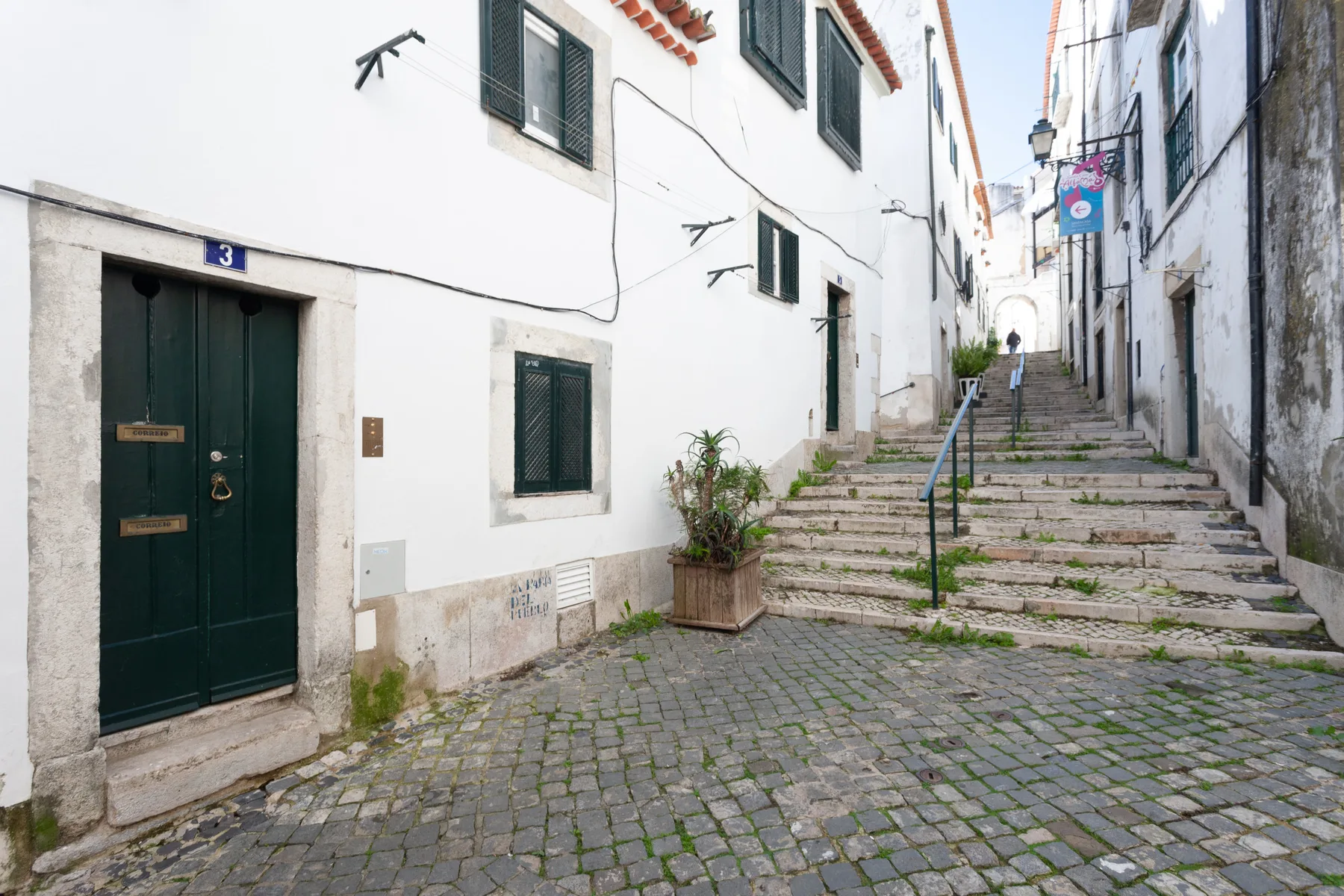Una calle empedrada con escalones de piedra entre edificios blancos.