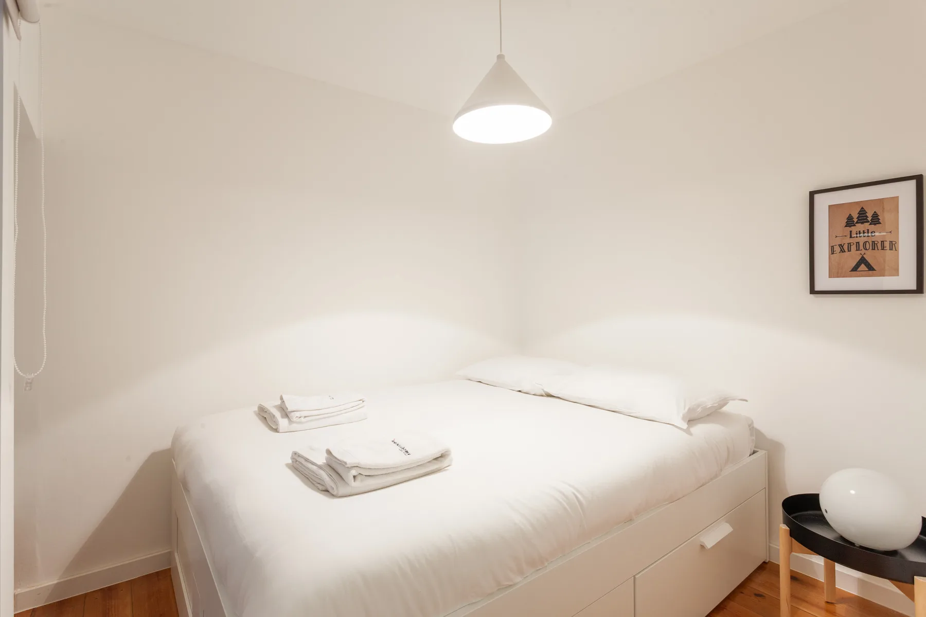 Un dormitorio luminoso con una cama blanca y toallas dobladas.