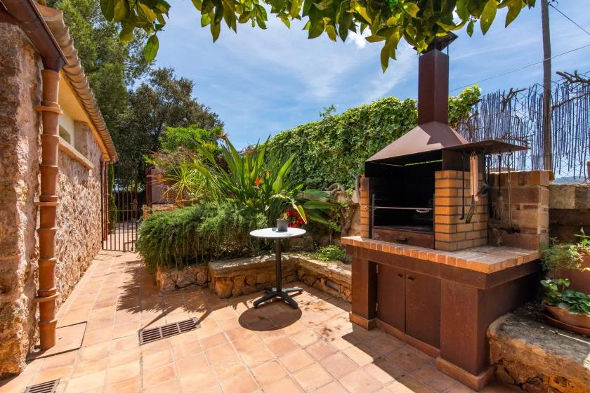 Un patio exterior de baldosas cuenta con una barbacoa empotrada y una mesa pequeña.