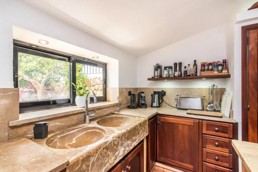 Una cocina con un fregadero bajo una ventana y armarios de madera.