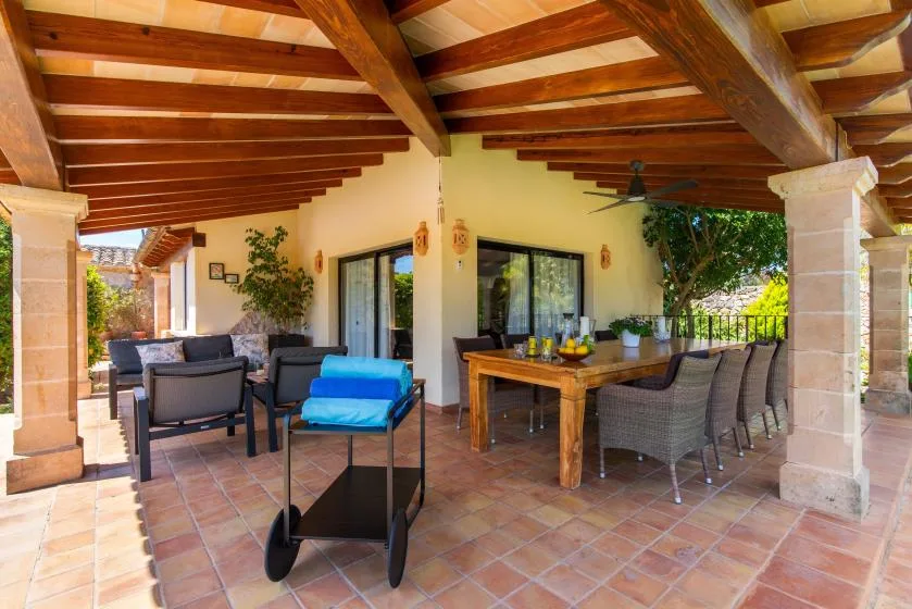 Un patio cubierto con asientos al aire libre y una mesa de comedor de madera.
