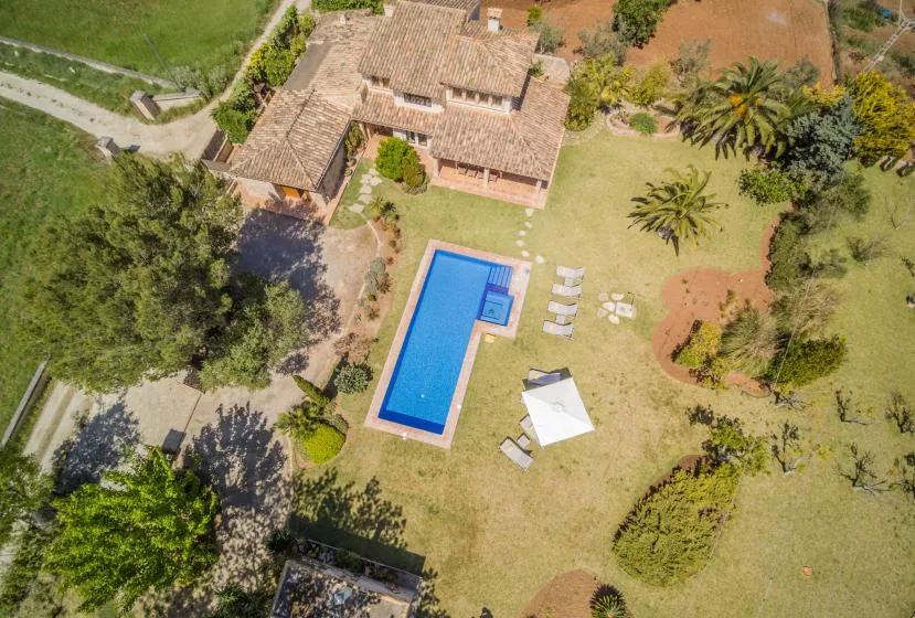 Una vista aérea muestra una casa, una piscina y el jardín circundante.