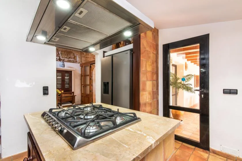 Una cocina con una estufa de gas sobre una encimera de piedra y una campana de acero inoxidable.