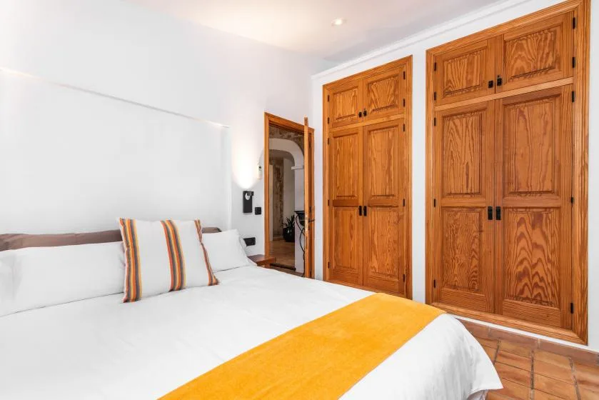 Un dormitorio con una cama bien arreglada y armarios empotrados de madera.