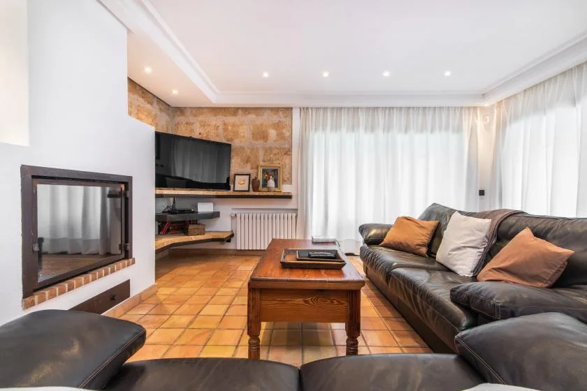 Una sala de estar con asientos oscuros, una mesa de centro de madera y un televisor.