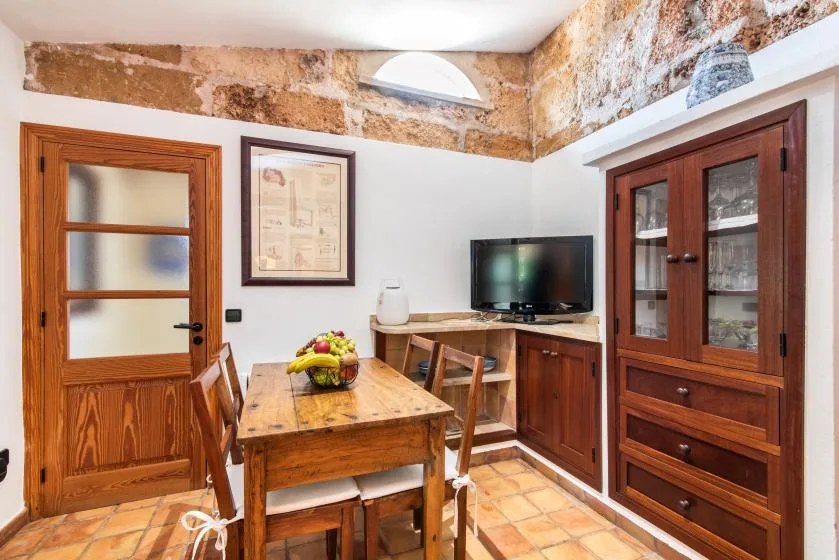 Un comedor rústico con una mesa de madera, sillas y un televisor sobre un mueble.