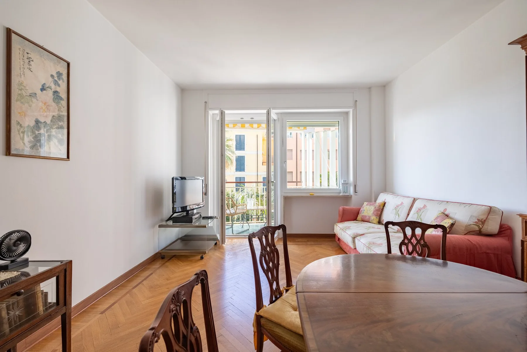 A bright living and dining room with seating beside large windows.