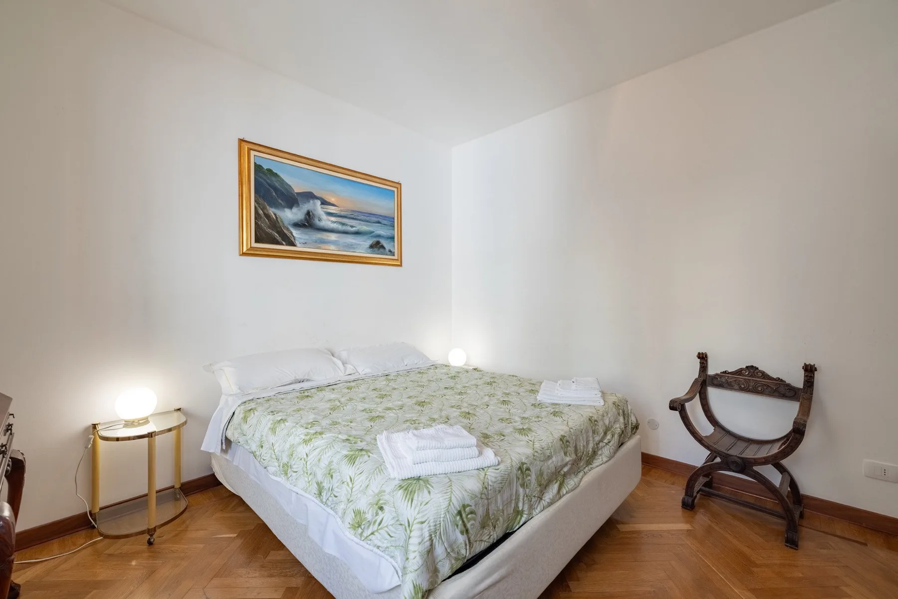 A bedroom with a bed covered in pale green patterned bedding.
