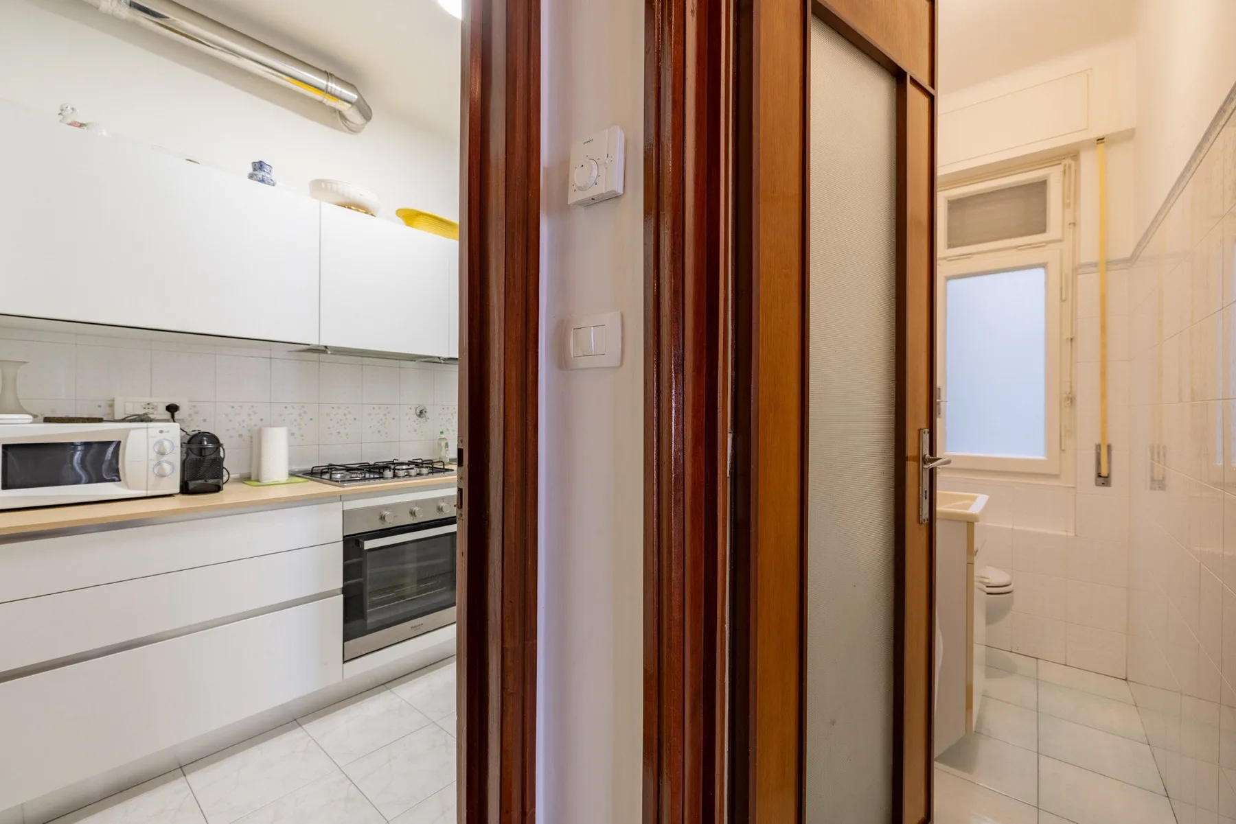 A kitchen and bathroom are visible through adjacent doorways.