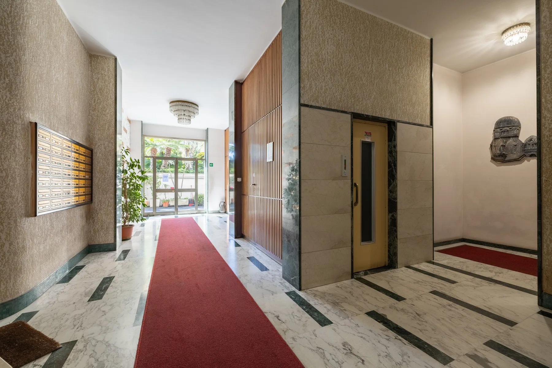 A building lobby with a red carpet runner and an elevator.