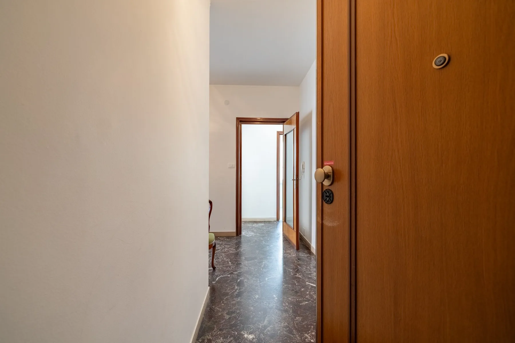 A hallway with a wooden door and a polished stone floor.