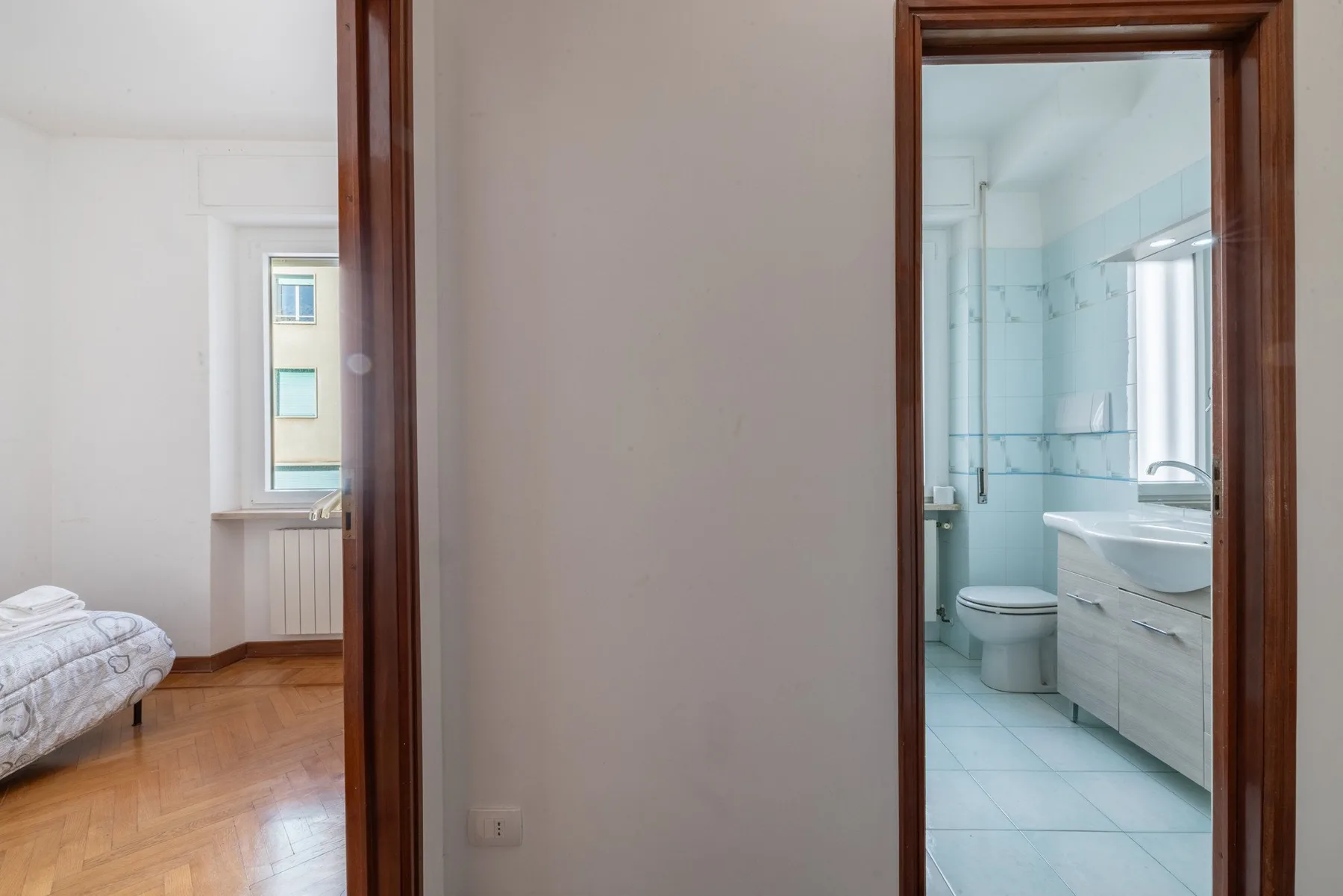 A hallway opens onto a bedroom and a bright bathroom.