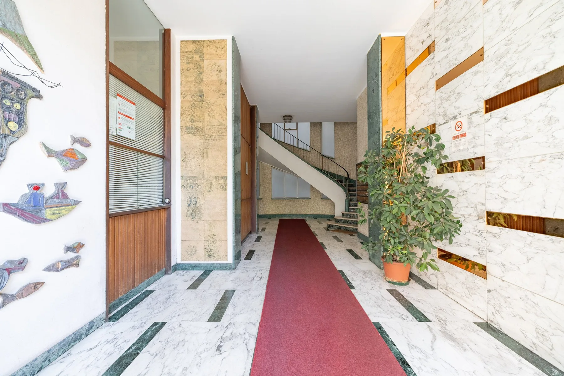 A building lobby with a red carpet leading toward a staircase.