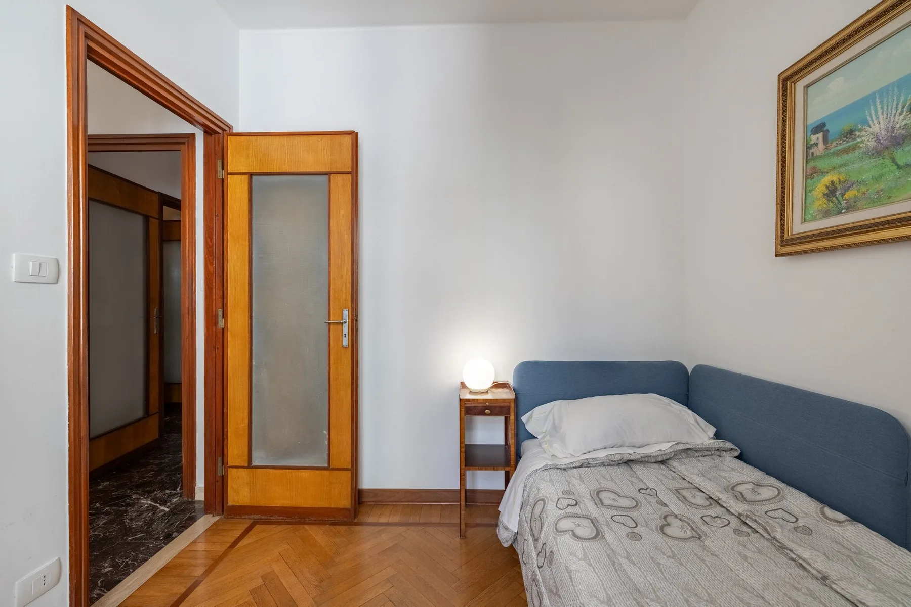 A bedroom with a bed, blue headboard, and wooden door.
