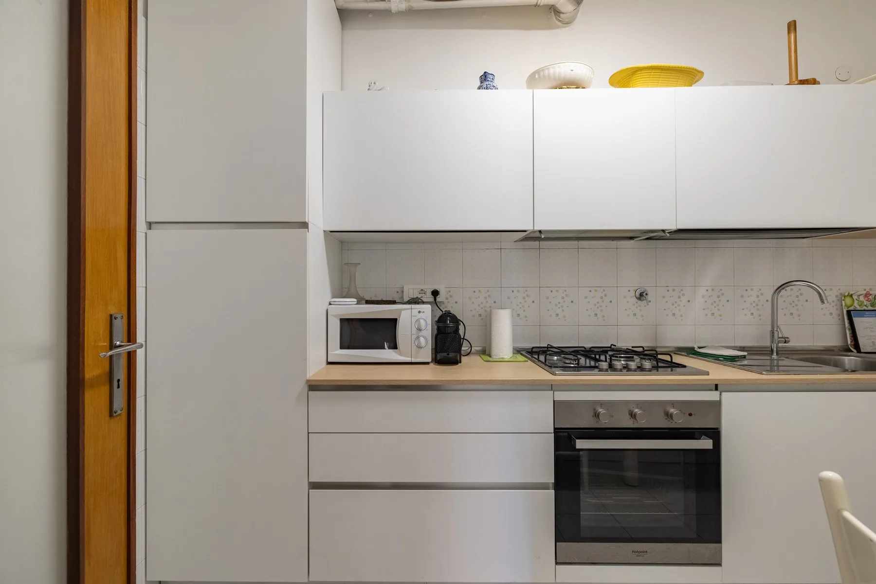 A compact kitchen with white cabinets, a countertop, and a built-in oven.